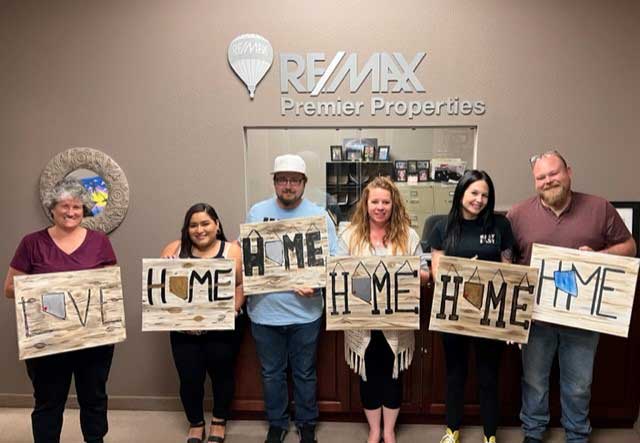 five people holding up signs that say home is my home